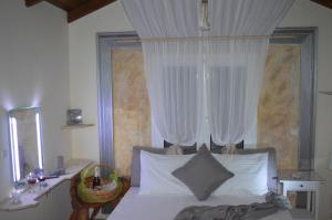 拉格尼西Villa Suites Lagonisi Luxury的一间卧室配有一张带白色窗帘的床和一张书桌