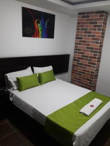 库库塔Hotel Valle de Beraca的一张铺有绿色和白色床单的床,并拥有砖墙