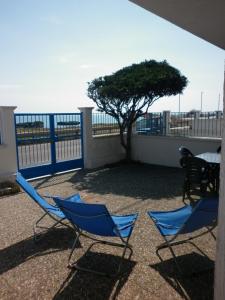 新福卡Villino sul mare的阳台上摆放着两把椅子和一张桌子,还有一棵树