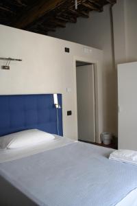 福萨诺Palazzo Sacco Hostello Fossano的一间卧室配有一张大床和蓝色床头板