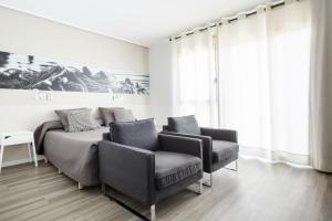 巴塞罗那德尔马尔校园公寓式酒店的一间卧室配有两把椅子、一张床和一幅画
