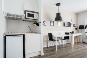 巴塞罗那德尔马尔校园公寓式酒店的厨房配有白色橱柜和桌椅