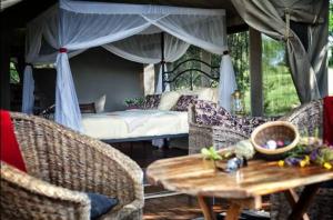 Kwa KuchiniaMbali Mbali Tarangire River Camp的配有一张床和一张桌子及椅子的房间
