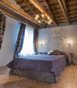 威尼斯San Marco Luxury apartments Muneghe的一间卧室配有一张大床和一个吊灯。