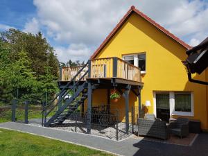 加兹尤瑟多姆Ferienwohnung Gleißner的黄色的房屋,设有楼梯和阳台
