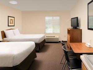 贝尔维尤WoodSpring Suites Omaha Bellevue, an Extended Stay Hotel的酒店客房设有两张床、一张桌子和一台电视。