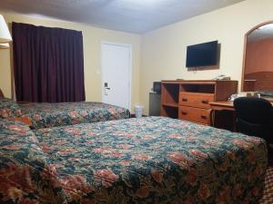 KeokukBudget Inn - Keokuk的酒店客房配有一张床、一张书桌和一台电视。