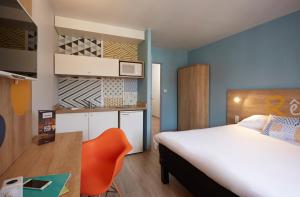 瓦朗西纳宝度酒店的酒店客房,配有床和橙色椅子