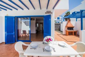 普拉亚布兰卡Villa Aitonita的庭院里设有蓝色门,配有白色的桌椅