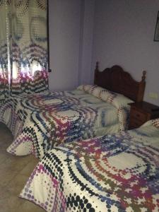 蓬特德乌梅Pension Meson Paz的一间卧室配有两张带色彩缤纷的棉被的床