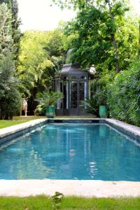 阿维尼翁神圣喜剧豪华套房旅馆的一座树木繁茂的房屋前的游泳池
