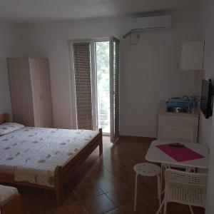 斯塔多伊兰Apartmani Milica Dojran的一间卧室配有一张床铺和一张桌子,还设有一间厨房
