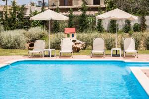 Kathiana阿瑞迪套房酒店的一个带椅子和遮阳伞的游泳池以及一座房子