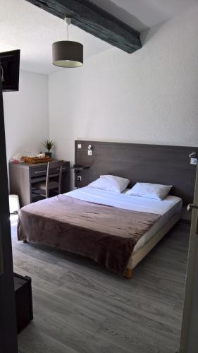 莫吉奥Mauguio Center Hôtel的一间卧室配有一张大床和一张书桌