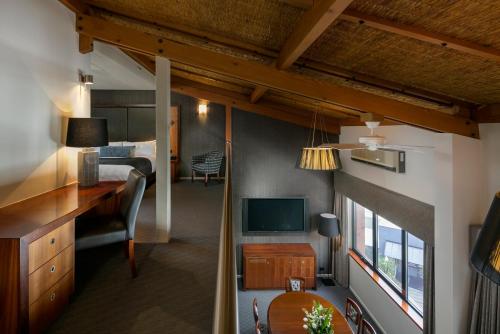 阿德莱德阿卡巴酒店的一间卧室配有一张床、一张书桌和一台电视