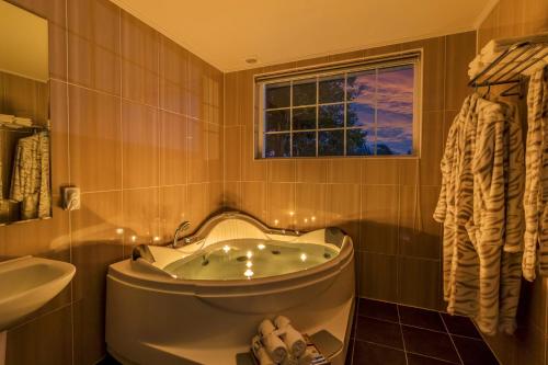西归浦市禧木屋酒店的带浴缸、水槽和窗户的浴室