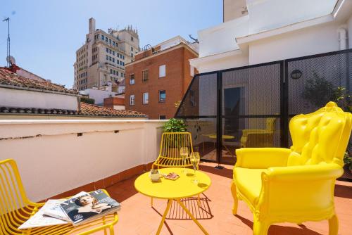 马德里马德里沃尔特旅馆的阳台配有黄色椅子和黄色桌椅