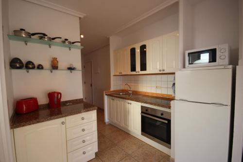 洛斯克里斯蒂亚诺斯Apartment Sur Sunrises, Los Cristianos的厨房配有白色橱柜和白色冰箱。