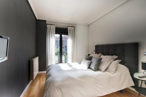 马德里市中心尊贵豪华公寓的一间卧室设有一张大床和一个窗户。