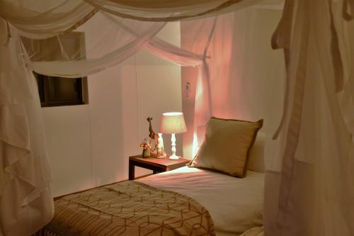 奥奇瓦龙戈Cheetah View Lodge的一间卧室配有一张床和一张带台灯的桌子