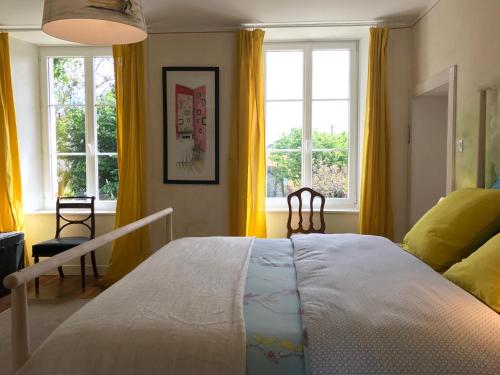 圣瓦斯特拉乌格L'Ermitage的一间卧室设有一张大床和两个窗户。