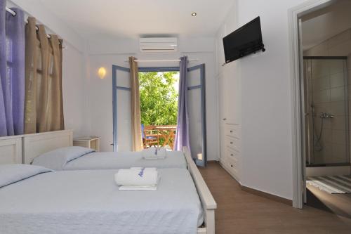 纳乌萨亚历山德罗斯公寓酒店的一间白色卧室,配有两张床和电视