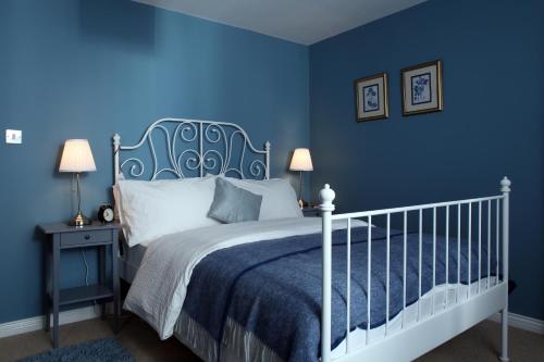 ComberCoach Road Cottages的蓝色的卧室设有白色的床和蓝色的墙壁