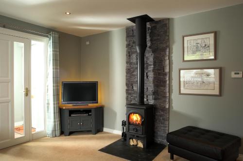 ComberCoach Road Cottages的客厅设有壁炉和电视。
