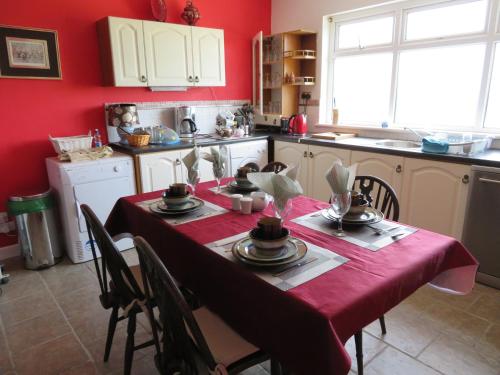 贝尔马利特Leam Cottage的厨房配有一张带红色桌布的桌子