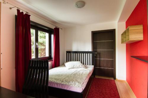 兹拉蒂博尔Apartments Cortina的一间卧室配有一张带红色窗帘的床和一扇窗户