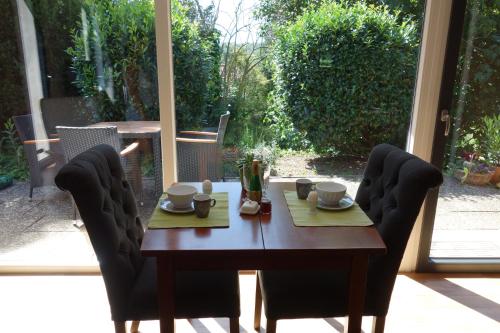 布劳恩费尔斯布罗因费尔斯费瑞豪斯度假屋的一张带两把椅子的木桌和一张带杯子和盘子的桌子