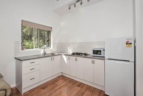 Gheerulla奥基溪私人休闲公寓的白色的厨房配有白色橱柜和窗户