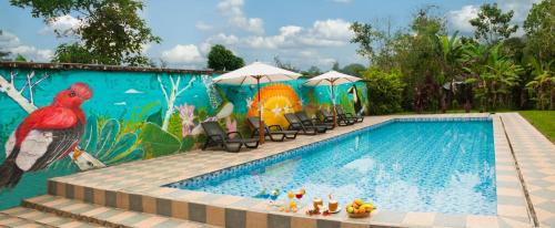 明多彼德拉宾馆的一个带壁画的游泳池,旁边是椅子和遮阳伞