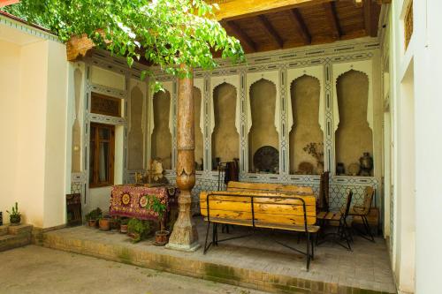撒马尔罕ANTICA Family Guest House的门廊,长凳,桌子和树
