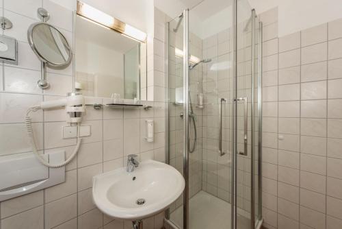 奥芬堡ibis Styles Offenburg City的一间带水槽和玻璃淋浴的浴室
