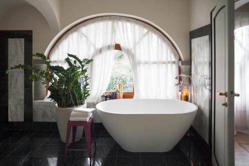 埃尔布斯科拉贝雷塔罗莱夏朵精品酒店的浴室配有大型白色浴缸和植物