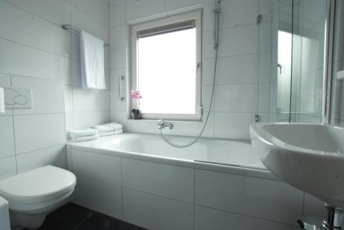 Riethoven仕乐途餐厅酒店的白色的浴室设有浴缸、卫生间和水槽。