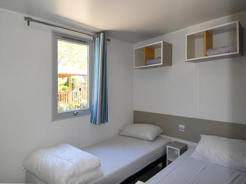 格里莫Var Mobil Home, Les Prairies de la Mer的客房设有两张床和窗户。