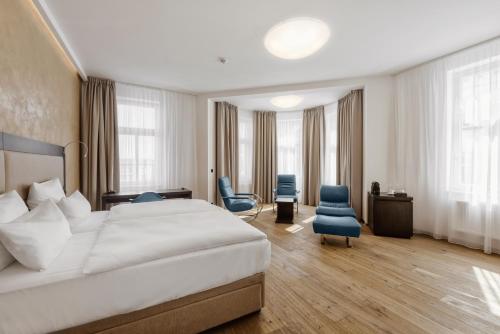 奥洛穆茨Theresian Hotel的酒店客房带一张大床和两张椅子