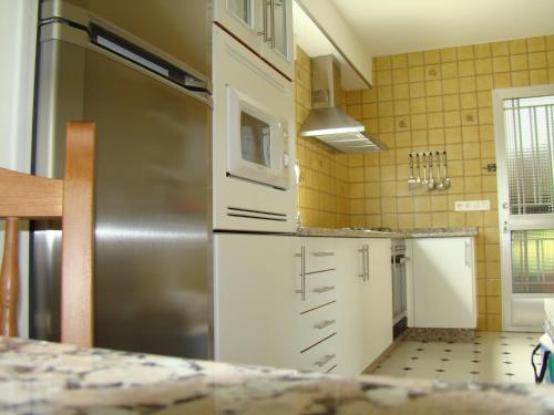 维拉加尔西亚·德·阿劳萨Apartamento Pedras的厨房配有白色橱柜和不锈钢冰箱