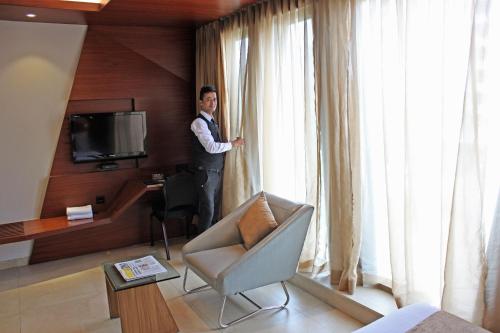 孟买Dragonfly Hotel- The Art Hotel的站在酒店房间,望向窗外的人