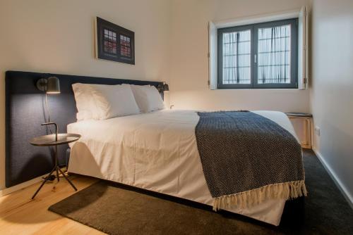 波尔图波尔图服务式公寓 - 阿尔瓦莱卡布拉尔的一间卧室设有一张大床和一个窗户。