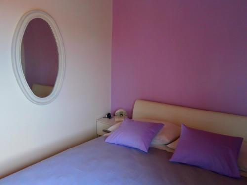 扎达尔绮丽吉恩公寓的一间卧室配有一张带紫色枕头的床和圆镜子
