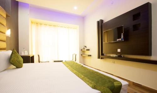 哈里瓦Vibhav Grand的卧室配有一张床铺,墙上配有电视