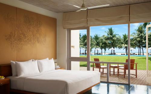 尼甘布杰特维茵酒店集团有限公司的一间卧室配有一张床,享有海滩美景