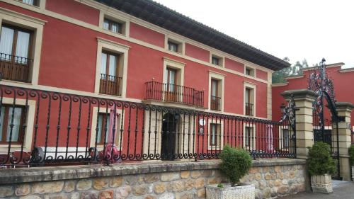 Villanueva de la PeñaPosada Santa Eulalia的前面有栅栏的红色建筑