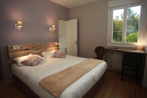 Ambazac旅行者之家酒店餐厅的一间卧室设有一张大床和一个窗户。