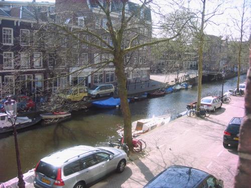 阿姆斯特丹Jordaan Canal View Apartment的一条有汽车停在河边的街道