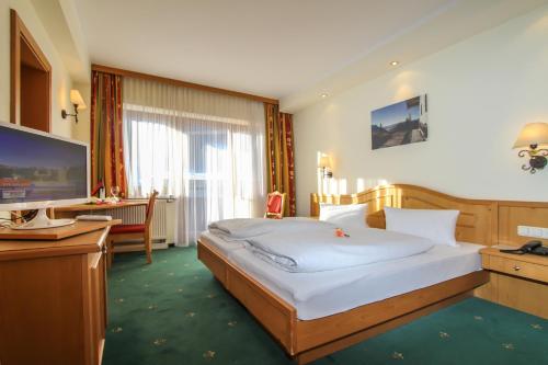 瓦德林Hotel Tiroler Adler Bed & Breakfast的一间卧室配有一张床、一张书桌和一台电视
