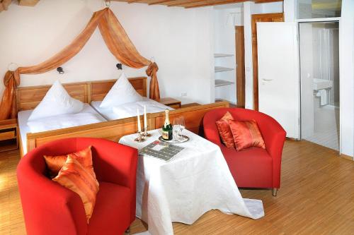 阿尔特海姆克罗斯特海力格克罗塞酒店的一间卧室配有两张红色椅子、一张桌子和一张床